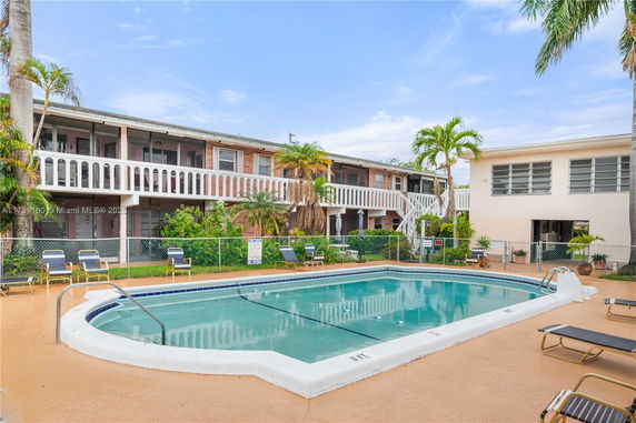 Outdoor view of a residential building with a swimming pool surrounded by lounge chairs.