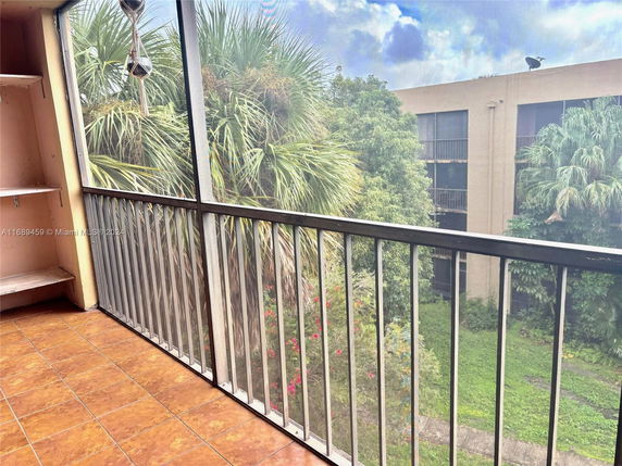 View from a balcony overlooking a garden area and adjacent building.