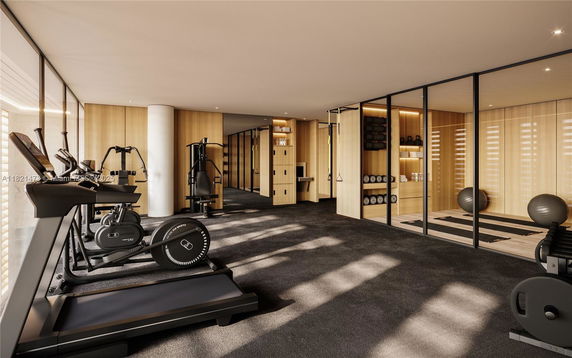 Interior view of a gym with exercise machines and yoga area.