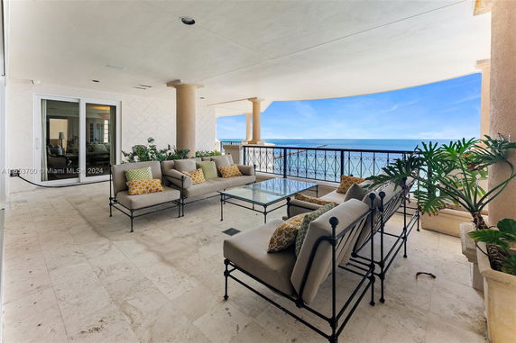 Covered balcony with seating area and ocean view.