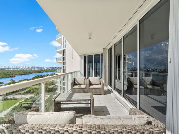 A balcony view showcasing outdoor seating arrangements and a scenic vista of a water body and surrounding landscape.