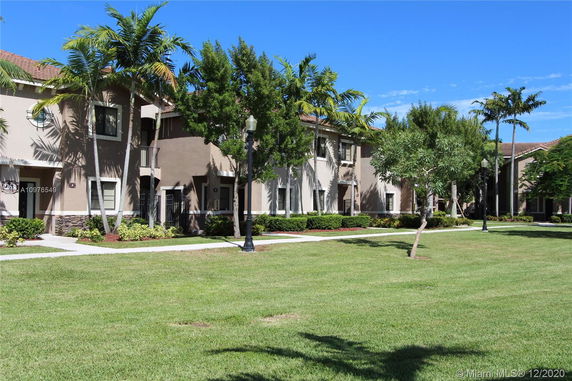 Front view of a two-story residential building with a landscaped walkway.