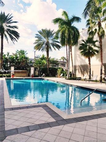 Outdoor swimming pool area with sun loungers and palm trees.