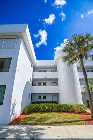 Front view of a multi-story building with white exterior and balconies.