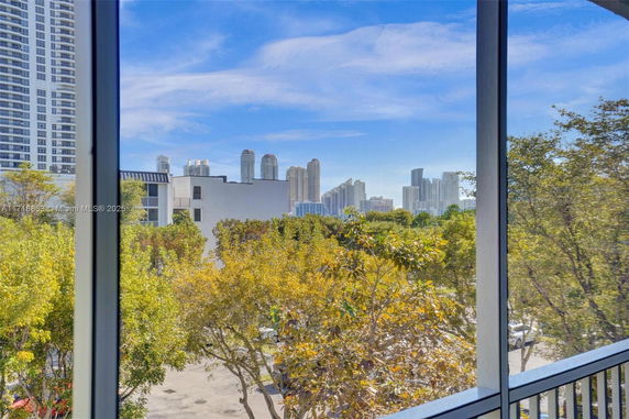 View from a building showing surrounding trees and distant skyscrapers.