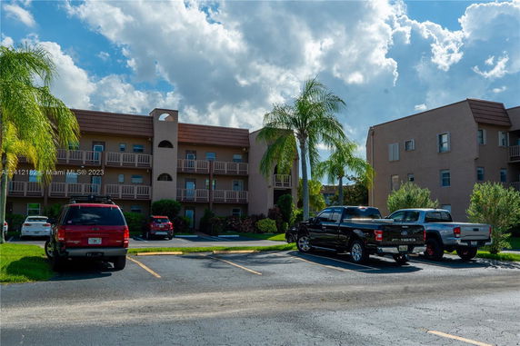 Outdoor parking area in front of a multi-story residential building with balconies.