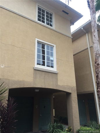 Front view of a multi-story house with a beige exterior and green doors.