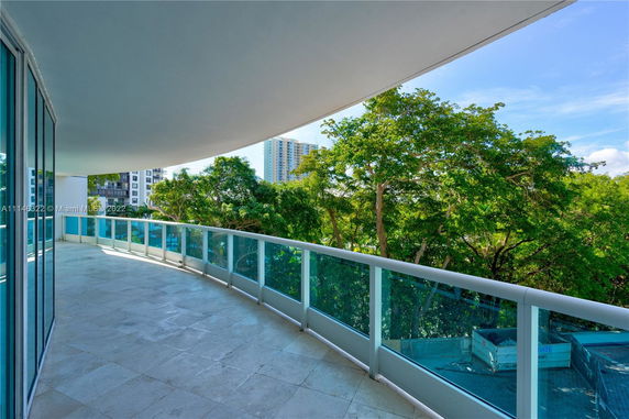 Wide balcony view overlooking trees and distant buildings.