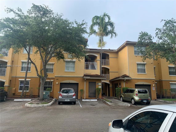 Front view of a multi-story residential building with balconies and parking area.