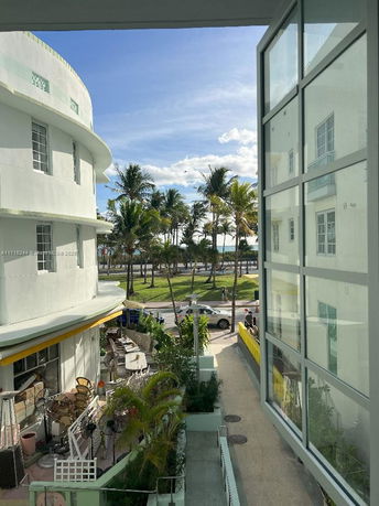 View from a building showing an outdoor seating area and a street lined with palm trees.