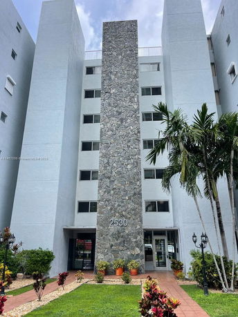 Front view of a multi-story building with stone facade and multiple windows.