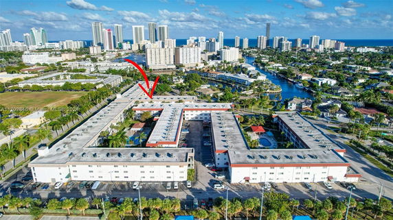 Aerial view of a multi-story building complex with surrounding urban landscape and water bodies.
