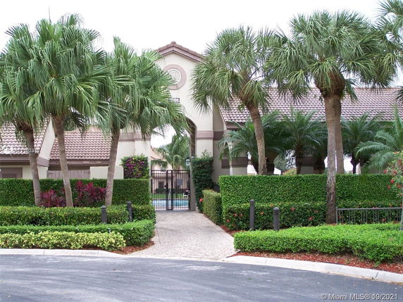 Front view of a building with a gated entrance and palm trees.
