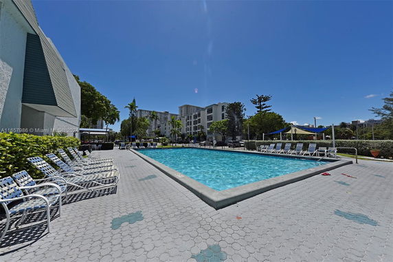 Outdoor swimming pool with lounge chairs and surrounding buildings.