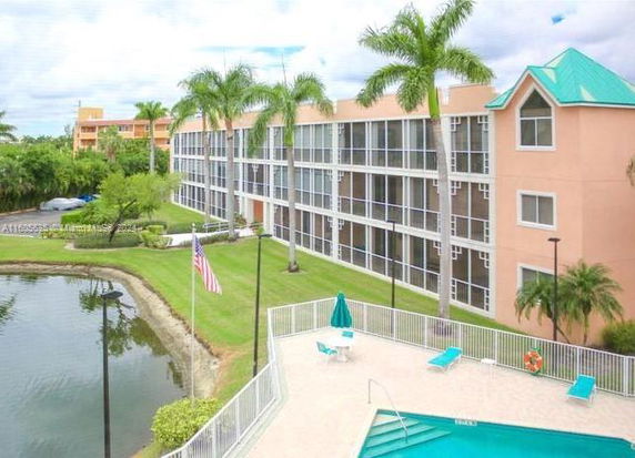 Outdoor view of a multi-story building with a swimming pool area and a small pond.
