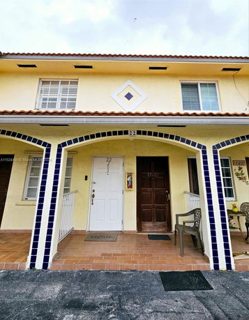 Front view of a two-story townhouse with arched entryway and balcony.
