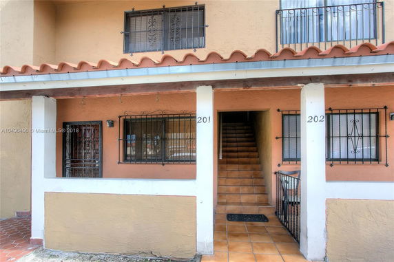 Front view of a two-story building with balconies and barred windows.