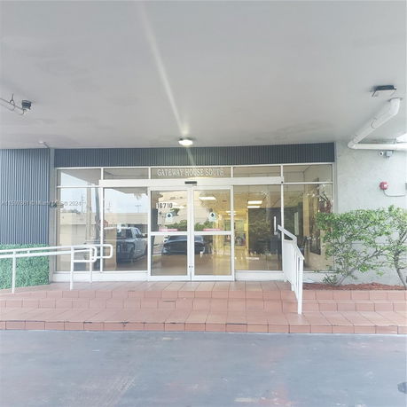 Front view of a building with glass entrance doors and a ramp.
