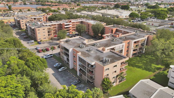 Aerial view of multiple residential apartment buildings with parking areas surrounded by greenery.