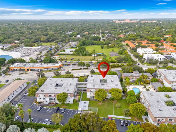 Aerial view of residential buildings with flat rooftops, parking areas, and a swimming pool.