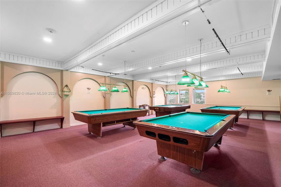 Indoor billiards room with multiple pool tables and overhead lighting.