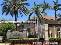 Front view of a house with palm trees and a sign.