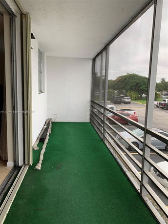 Screened balcony view showing part of a parking area and nearby greenery.