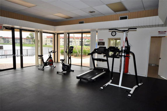 Indoor gym area with exercise equipment and large windows.