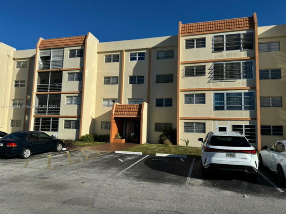 Front view of a four-story apartment building with parking spaces.