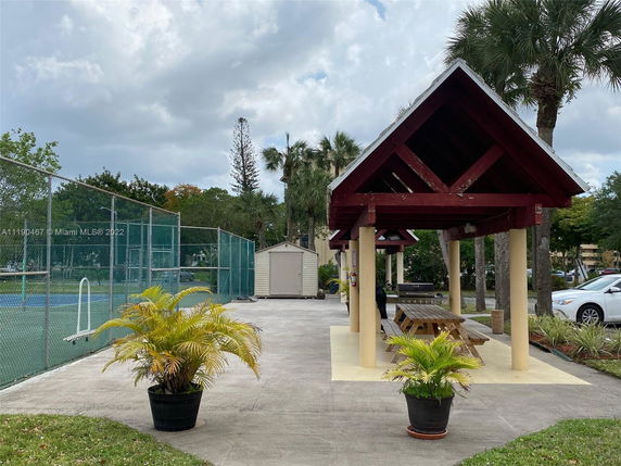Outdoor area with a tennis court and covered seating area.