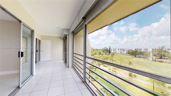 View from a balcony showing a distant apartment complex and green space.