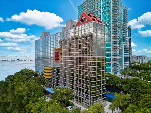 Front view of a modern multi-story building with glass facade and unique architectural features.