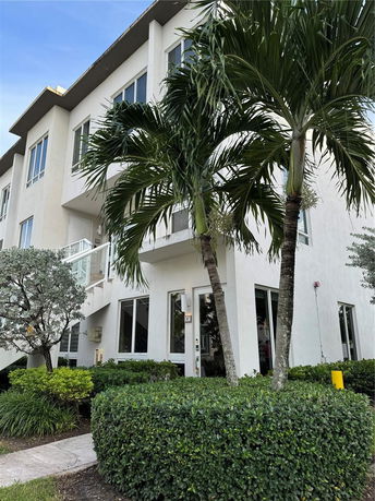 Front view of a multi-story building with large windows and surrounding greenery.