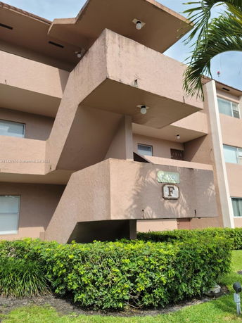 Front view of a multi-story building with a beige exterior and balconies.