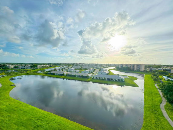 Aerial view of a residential area with multiple buildings and a large lake under a partly cloudy sky.