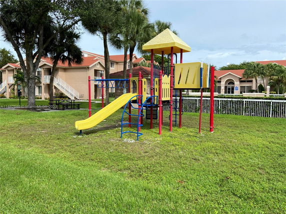 Outdoor playground with slides and climbing equipment, in front of residential buildings.