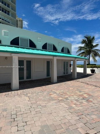 Front view of a building with a teal roof and arched windows.