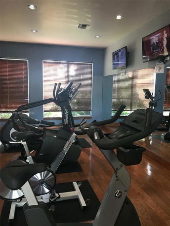 Indoor gym area with exercise equipment and television screens.