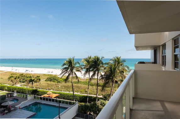 Balcony view overlooking a beach and ocean with palm trees.