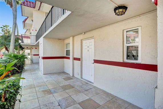 Entrance area of a building with white walls, red stripe, and tile flooring.