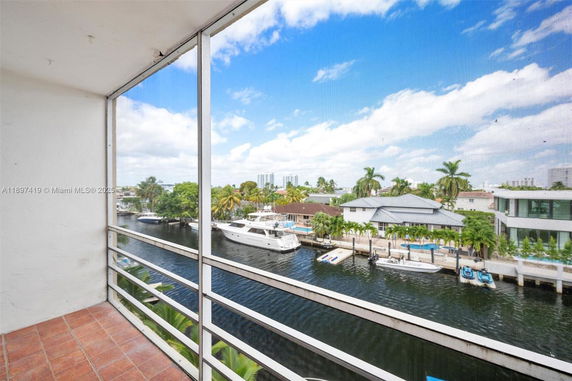Panoramic view of canal-front properties with boats and palm trees from a balcony.