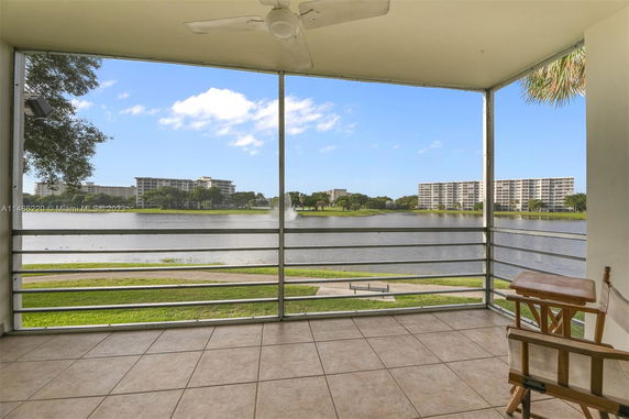 View from a tiled balcony overlooking a lake with buildings in the distance.