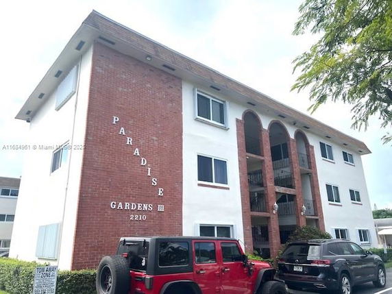 Front view of a multi-story apartment building with arched balconies and a brick facade.