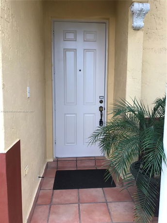 Front entrance of a house with a white door and terracotta tiles.