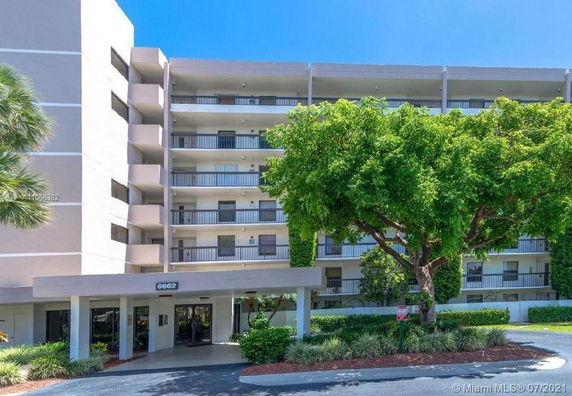 Front view of a multi-story residential building with balconies and a covered entrance.