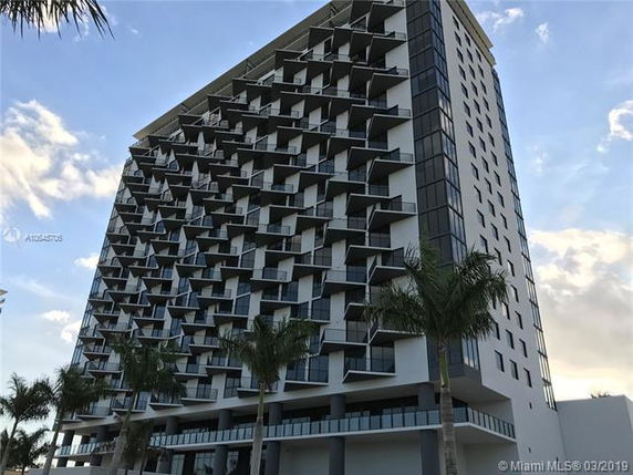 Front view of a multi-story modern building with unique balcony designs.
