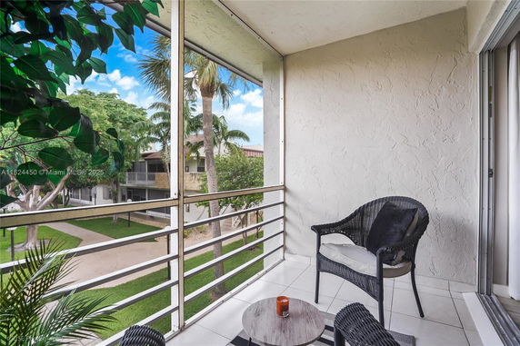 View from a balcony overlooking a courtyard with trees and a building.