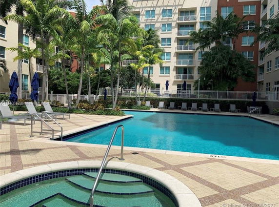 Outdoor swimming pool area with lounge chairs and surrounded by tall residential buildings.