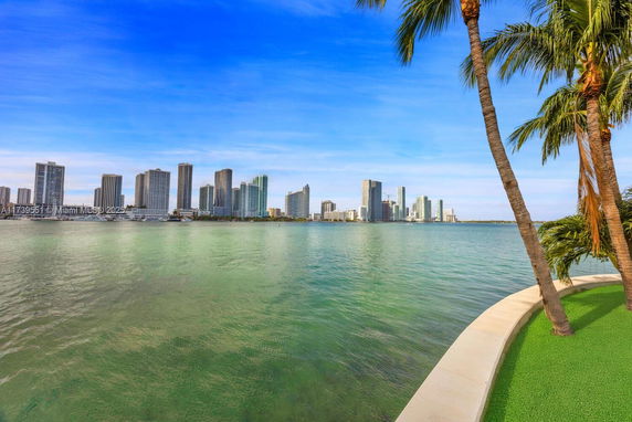 Panoramic view of a waterfront cityscape with skyscrapers and palm trees.