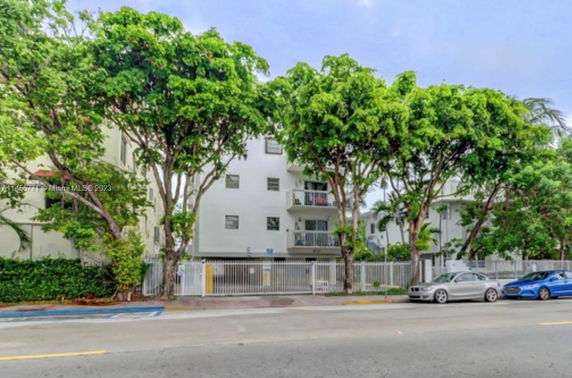 Front view of a multi-story residential building with balconies and a gated entry.